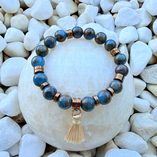 Handgefertigtes Naturstein-Armband in Blau- und Erdtönen mit Quaste auf weißen Steinen