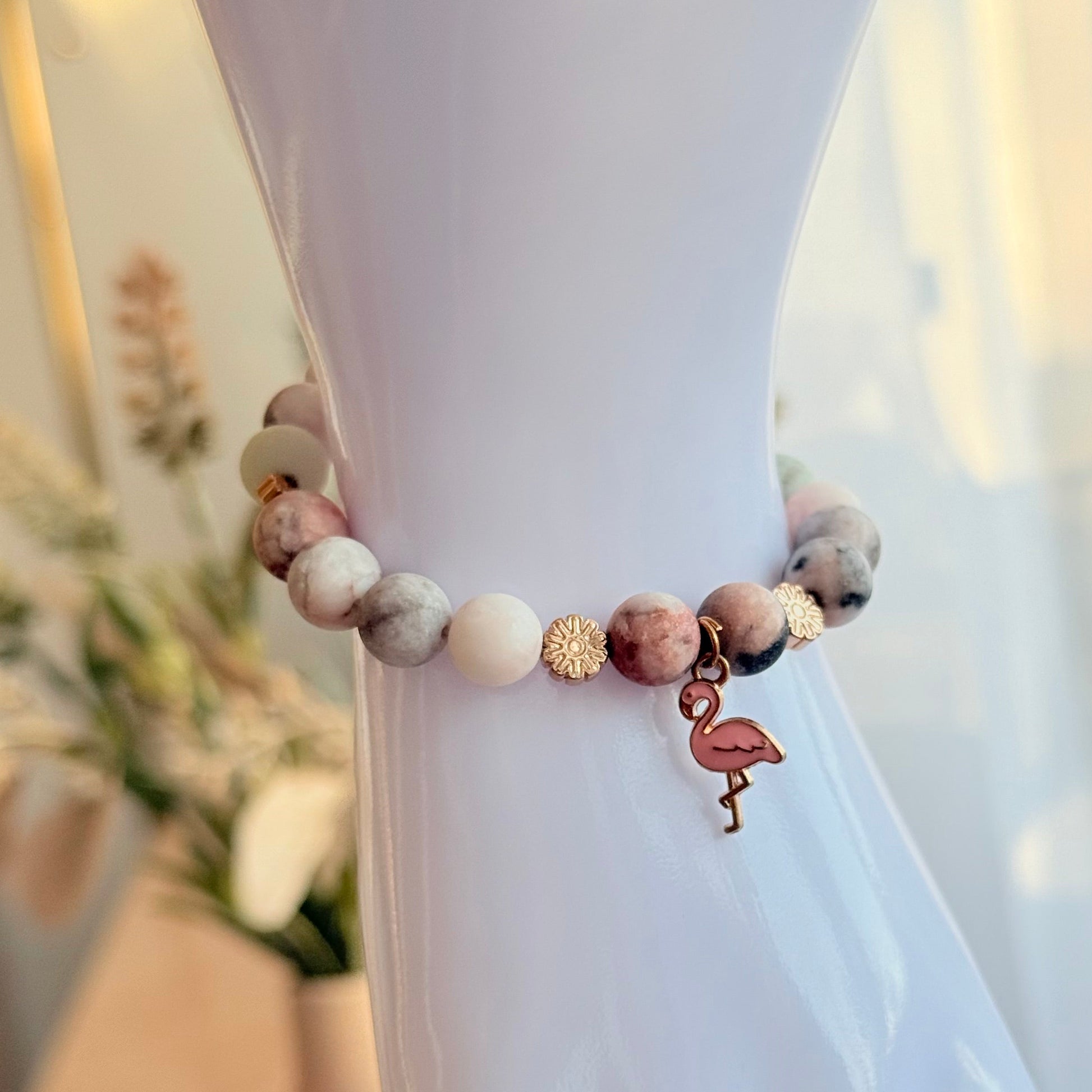 Natursteinarmband mit Flamingo-Anhänger und goldfarbenen Hämatitperlen am Handmodell