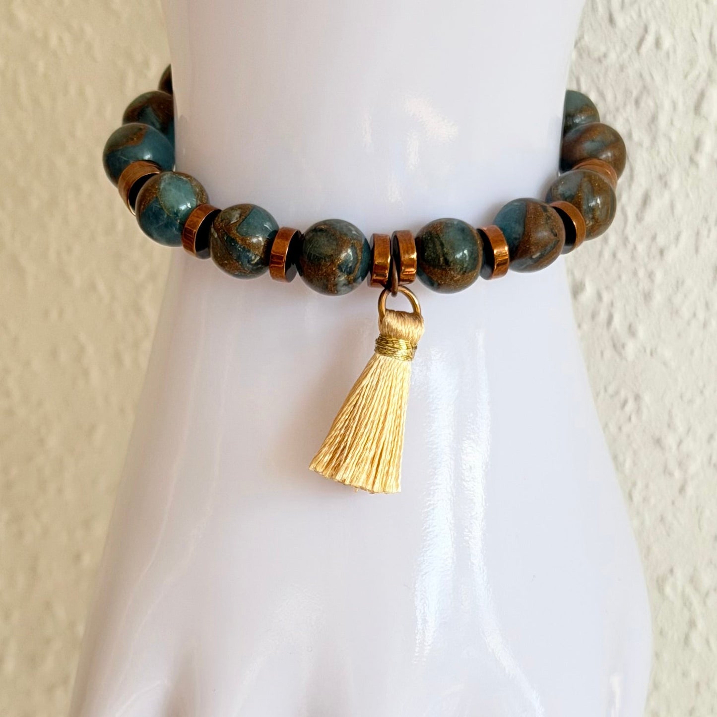 Handgefertigtes Naturstein-Armband in Blau- und Erdtönen mit Quaste am Handgelenk