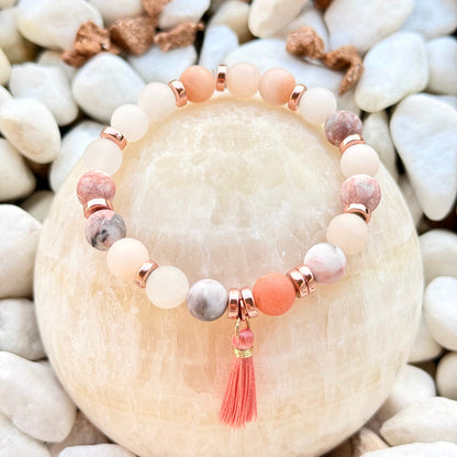 Natursteinarmband mit rosa Quaste und roségoldfarbenen Hämatitperlen auf Stein