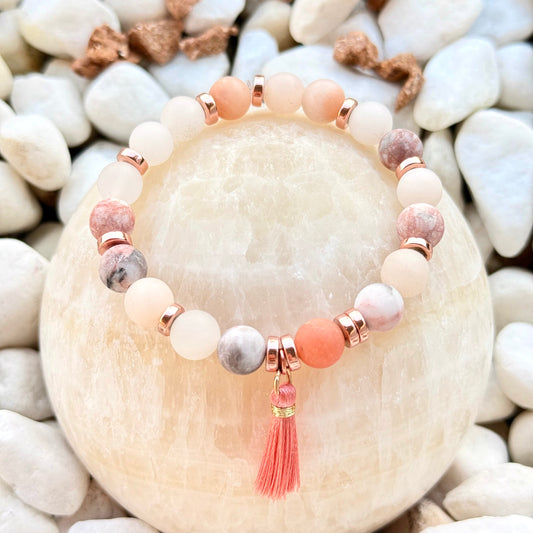 Natursteinarmband mit rosa Quaste und roségoldfarbenen Hämatitperlen auf Stein